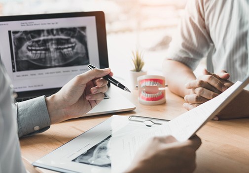 Dentist discussing X-rays with patient at desk